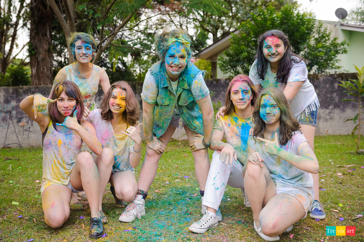 Meninas todas coloridas posando para foto com pó de happy holi de todas as cores para fotografia de book de 15 anos da amiga
