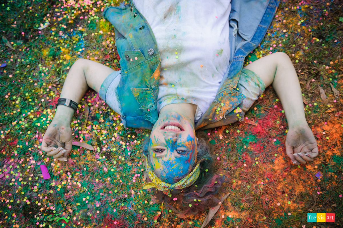 Menina toda colorida com pó de happy holi de todas as cores para fotografia divertida de book de 15 anos da amiga