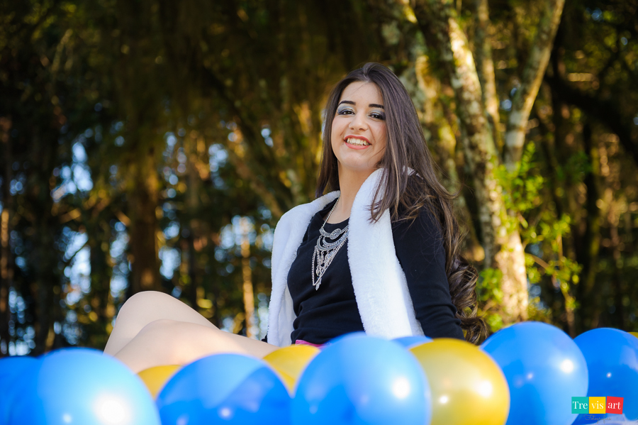 Menina de 15 anos sorrindo em seu book de 15 anos com balões coloridos no memorial ucraniano em curitiba