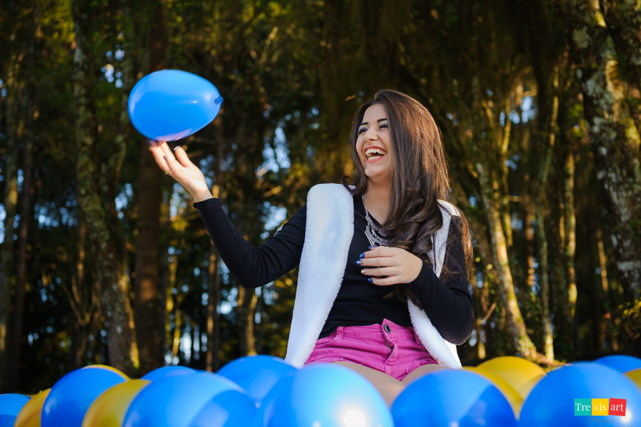 Menina de 15 anos sorrindo em seu book de 15 anos com balões coloridos azul e dourado no memorial ucraniano em curitiba