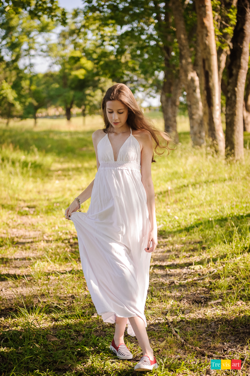 Menina caminhando com vestido branco no Haras no seu book de 15 anos
