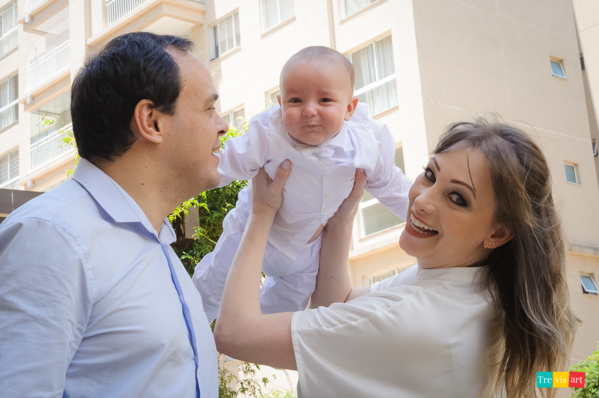 pais brincando com bebê de aviãozinho no almoço de batismo