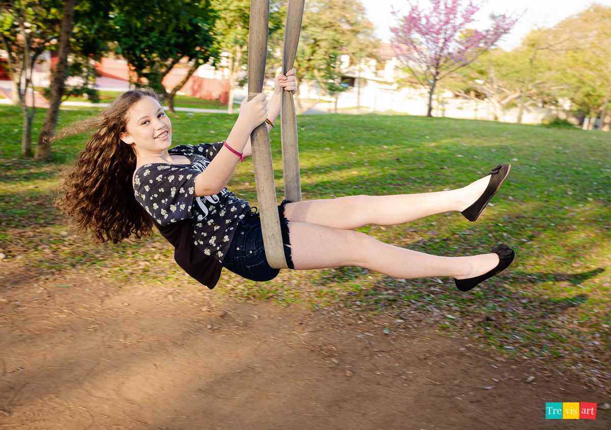 fotografia externa de família com menina se  balançando no balanço de árvore na praça do paraná clube em curitiba