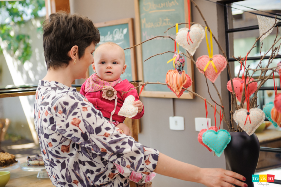Foto aniversariante arrumando detalhes da decoração da festa infantil e sorrindo com a mãe