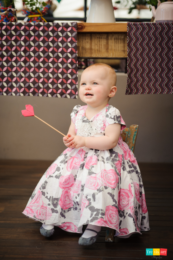 Foto menina brincando sentada na sua cadeirinha na frente da mesa do bolo na sua festa de aniversario