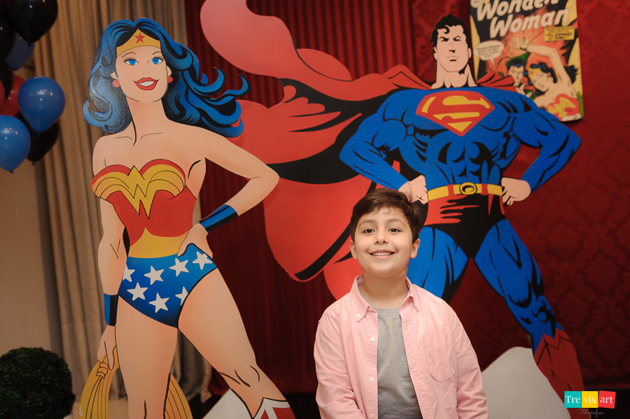 Foto aniversariante na decoração da festa infantil com a Mulher Maravilha e Superman.