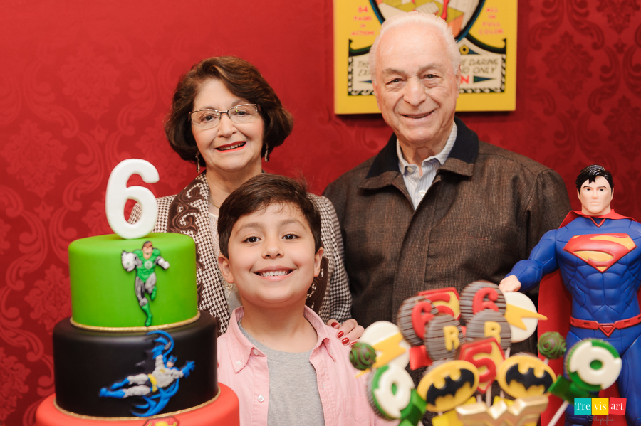 Foto aniversariante com avós na mesa do bolo da festa, tema Super Heróis. Buffet Mundo Kids.
