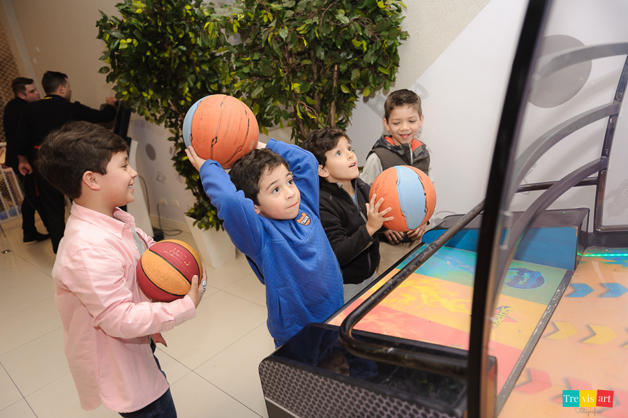 Foto aniversariante brincando no basquete com convidados na sua festa infantil.