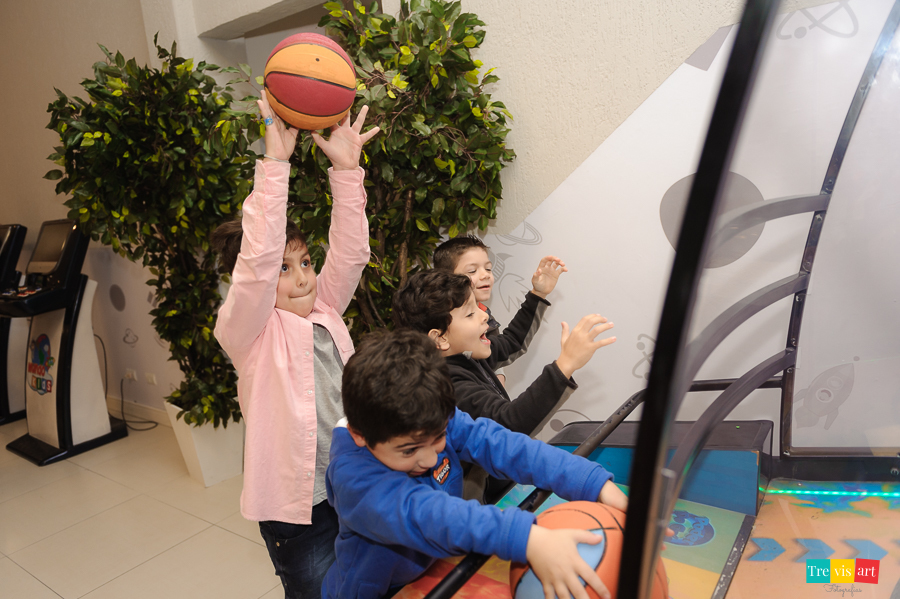 Foto aniversariante brincando no basquete com convidados na sua festa infantil.