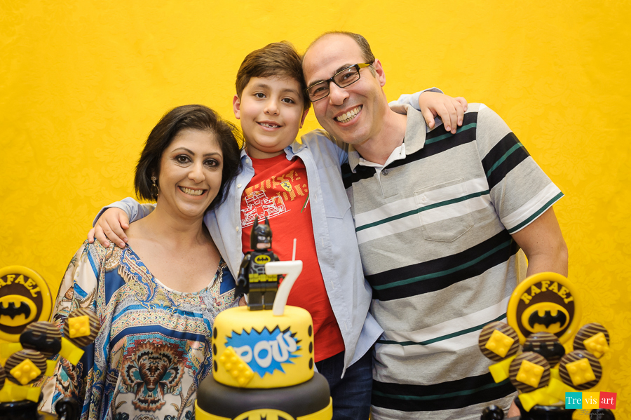 Foto aniversariante com os pais na mesa do bolo, festa infantil tema Lego Batman.
