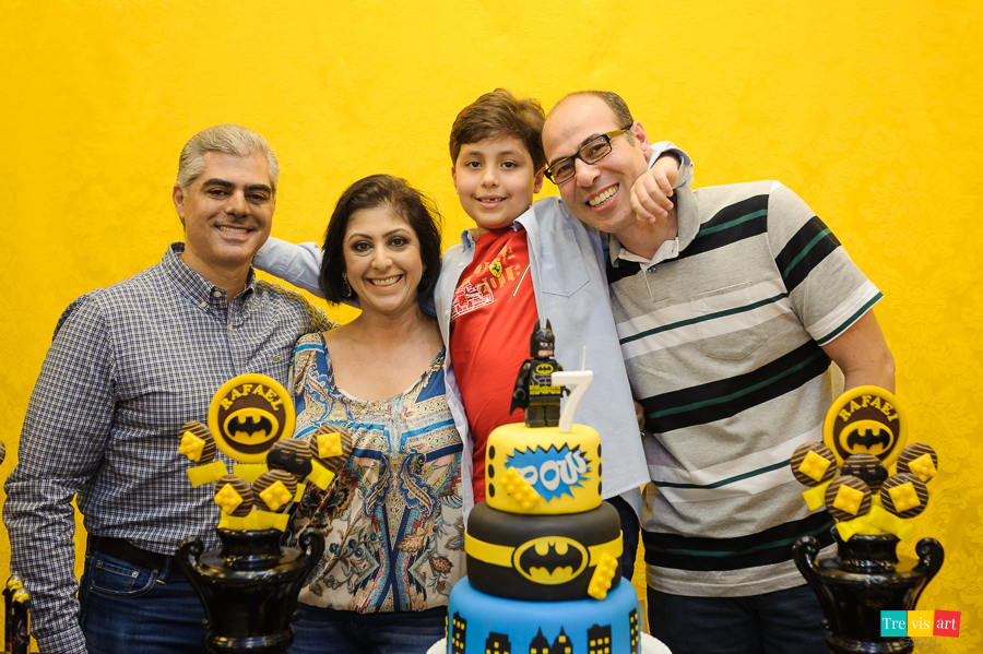 Foto aniversariante com os pais e padrinho na mesa do bolo, festa infantil tema Lego Batman.