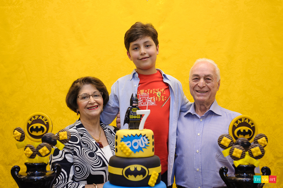 Foto aniversariante com os avós na mesa do bolo, festa infantil tema Lego Batman.