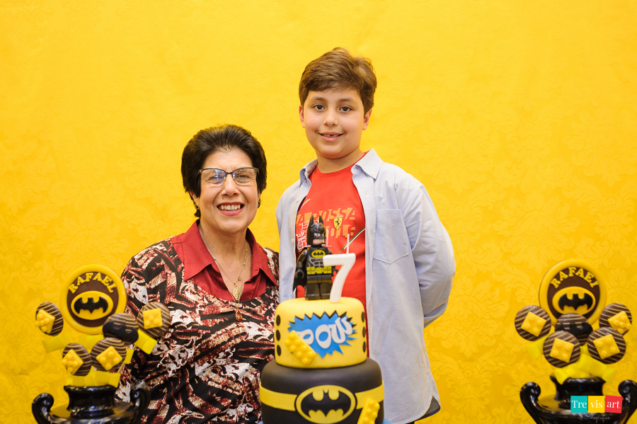 Foto aniversariante com a avó na mesa do bolo, festa infantil tema Lego Batman.