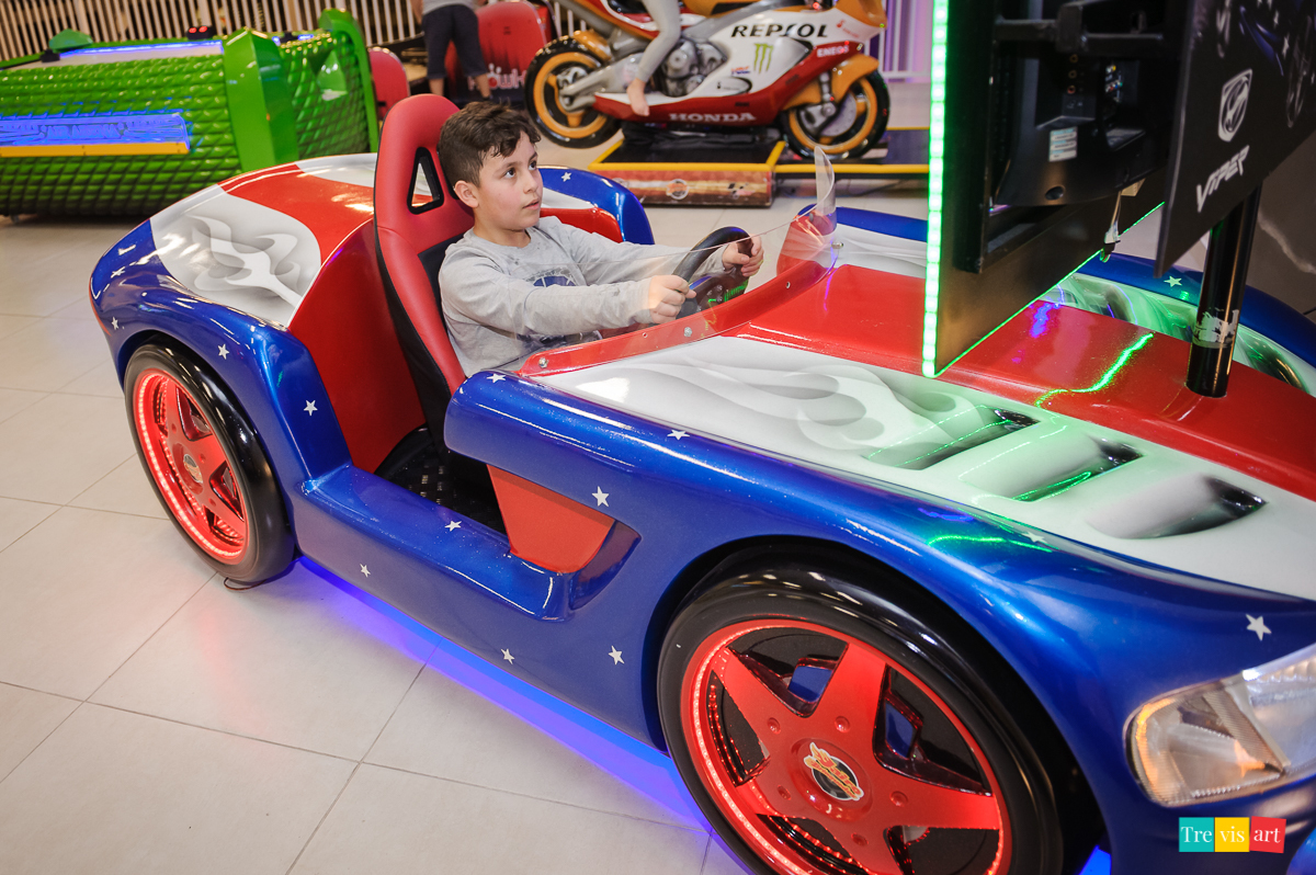 Foto aniversariante brincando no simulador de carro no buffet de festa infantil.