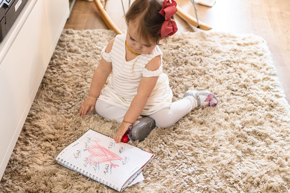 menina desenhando no chão da sala de casa 