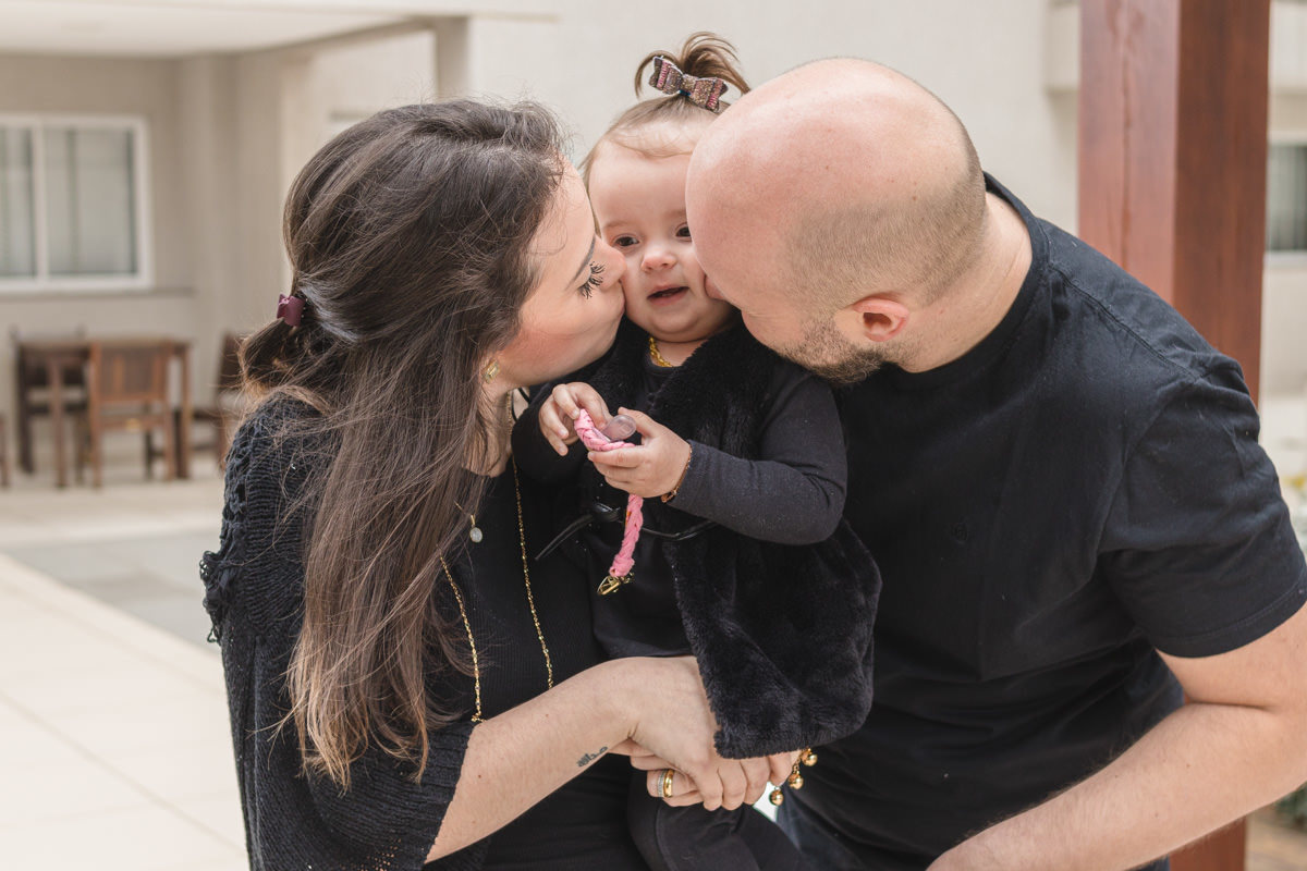 Pai, mãe beijando a filha  