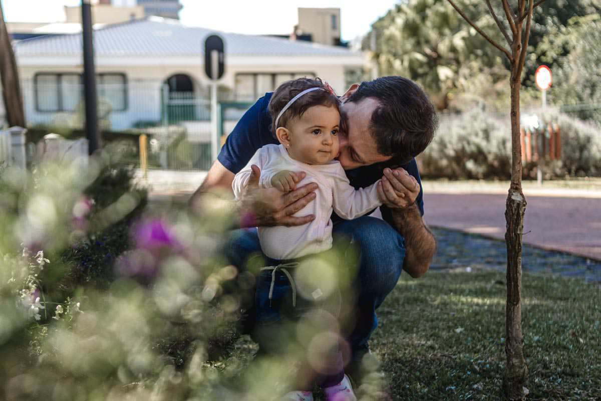 pai abaixado brincando com a filha