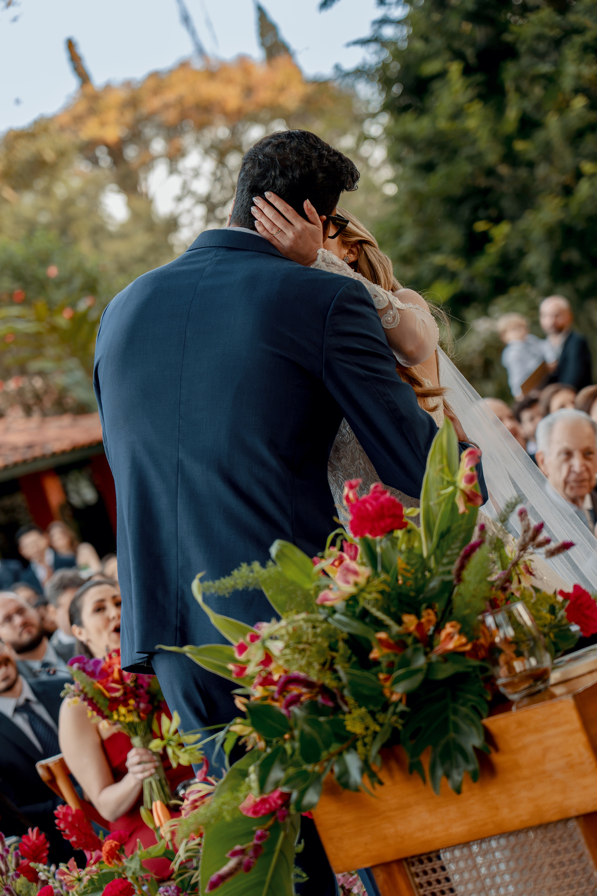 Noivos vistos de costas durante um momento da cerimônia no jardim