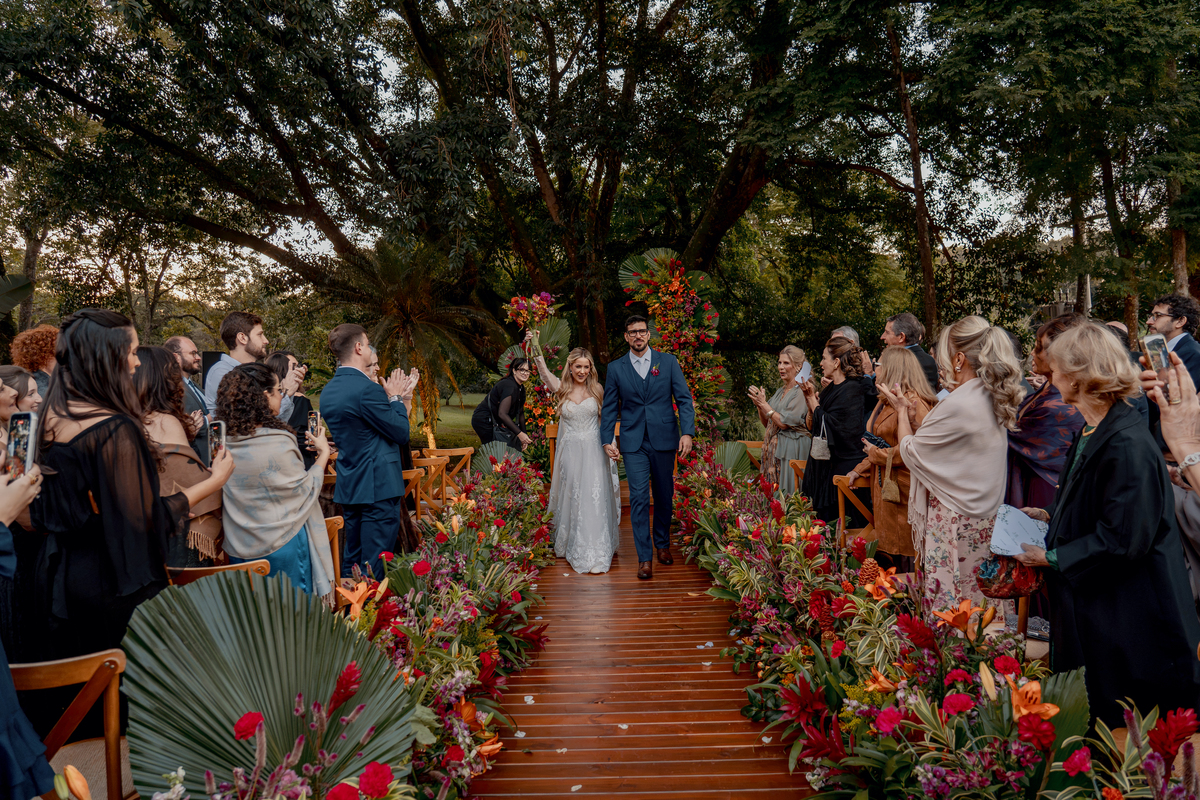 Caminho da cerimônia cercado por flores, árvores e convidados