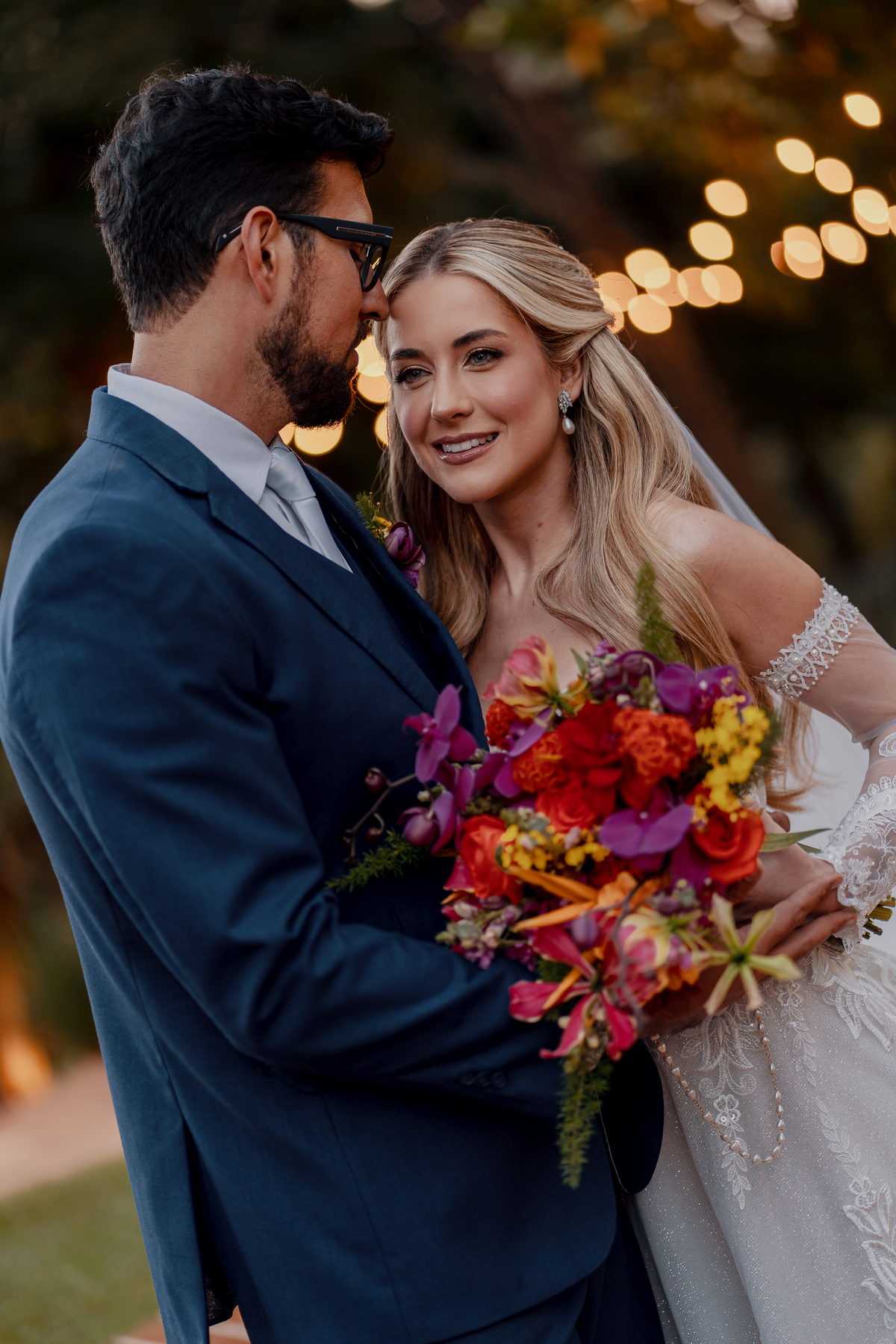 O vestido e o buquê de Juliana ganham destaque enquanto o casal caminha pelo jardim.