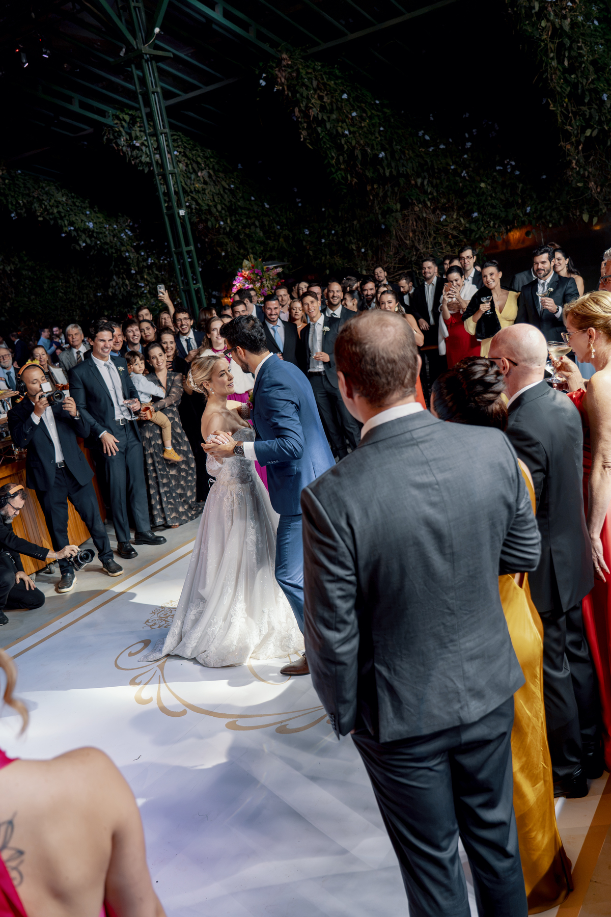 O casal dança no centro da pista diante dos familiares e amigos.