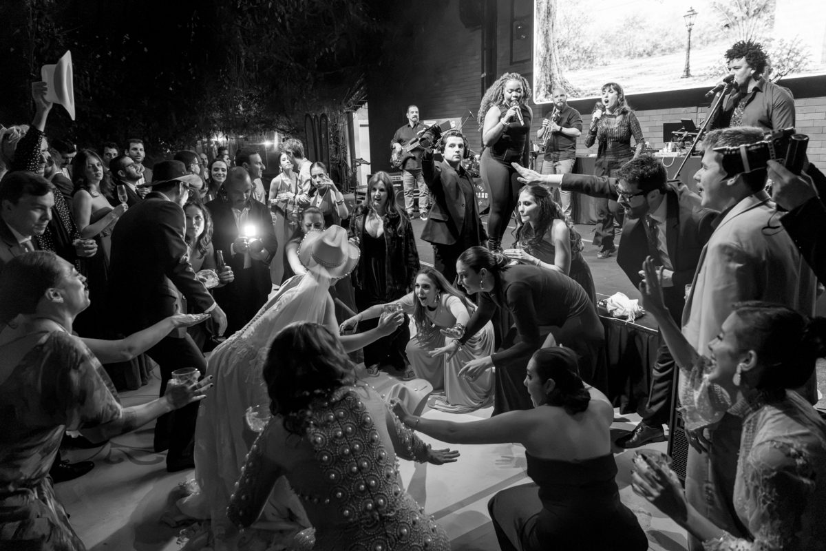 Registro em preto e branco da pista de dança, com os convidados reunidos durante a celebração.