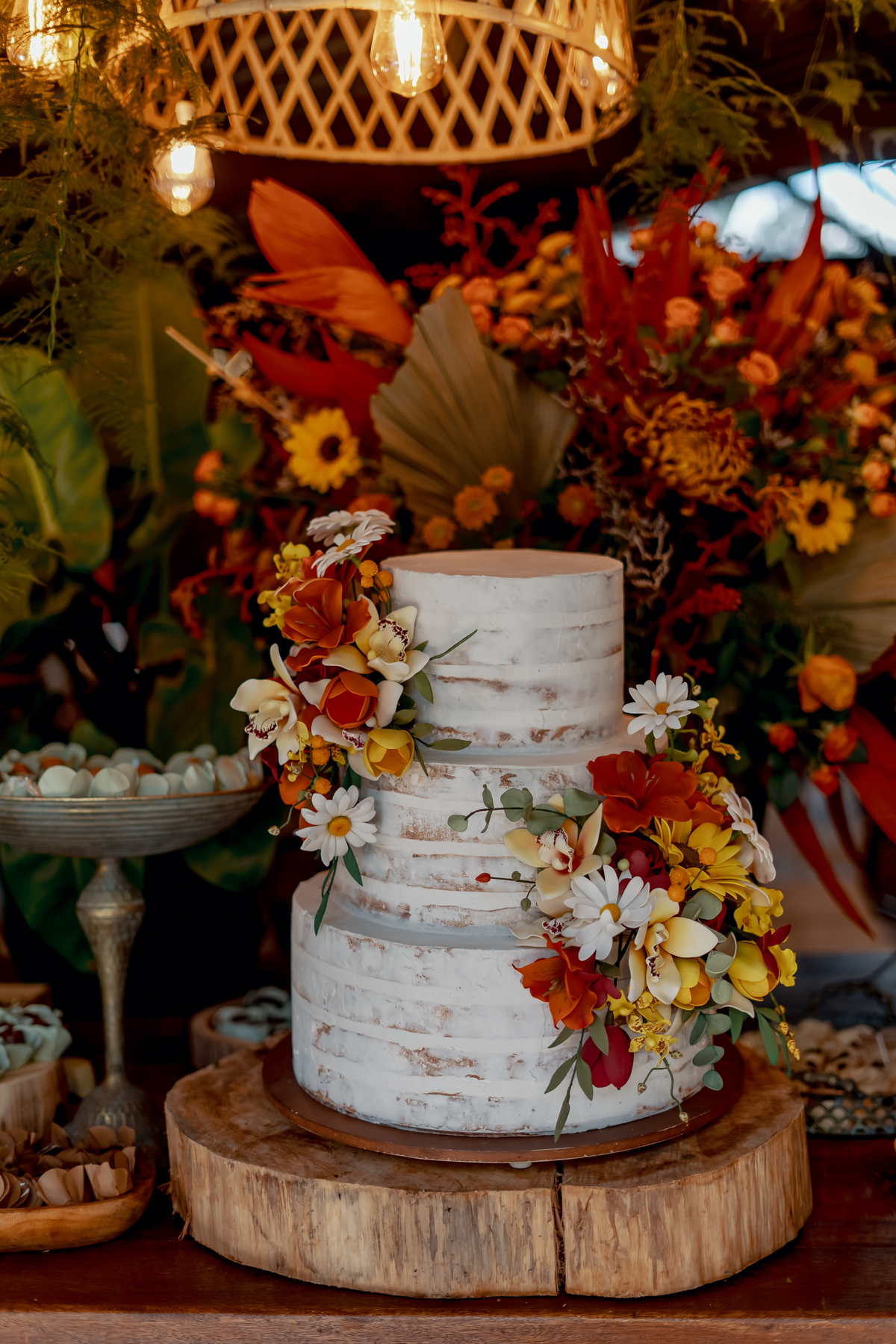 Bolo de casamento de Fábio e Yasmin decorado com flores e elementos naturais, compondo a identidade visual da celebração na fazenda.