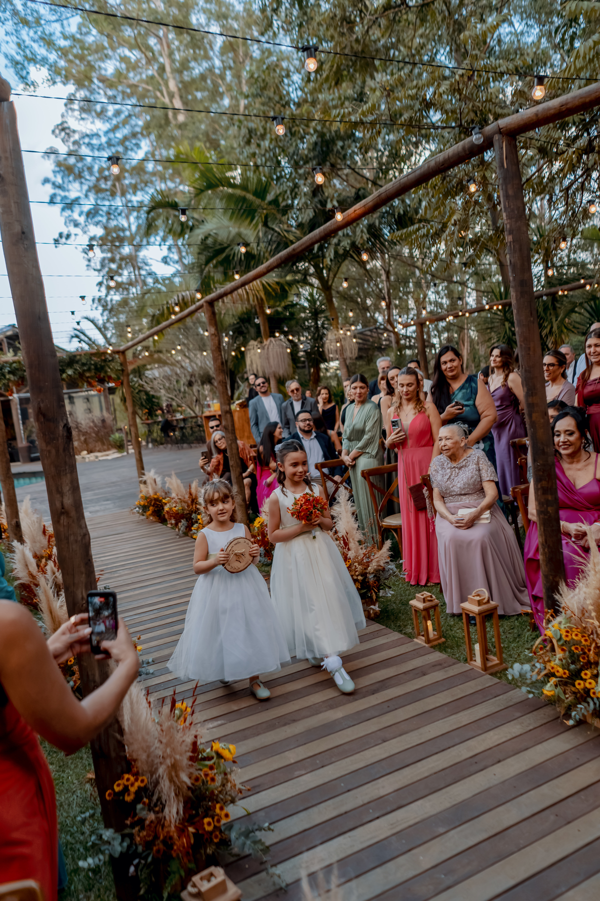 Convidados reunidos diante do altar durante o casamento de Fábio e Yasmin, com a natureza ao redor da cerimônia ao ar livre.