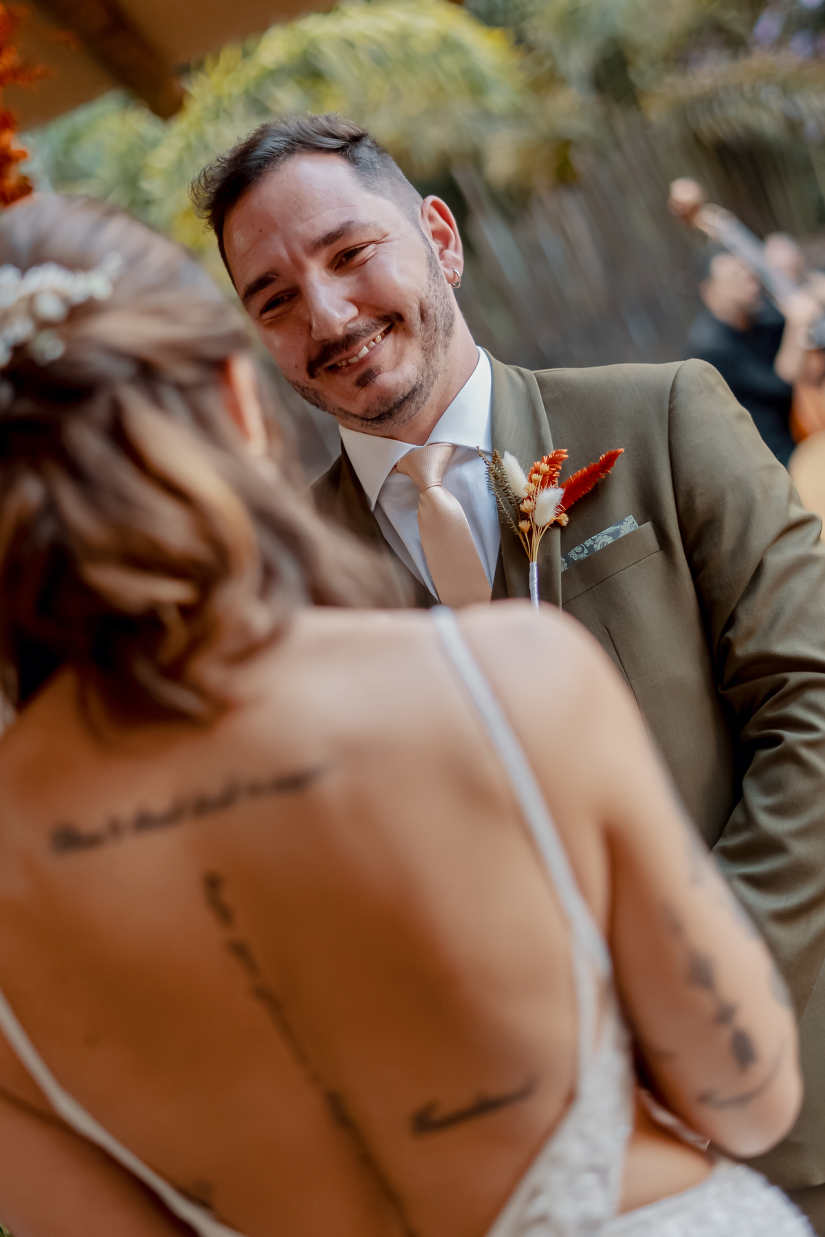 Detalhe do traje de Fábio durante a cerimônia, com o buquê de Yasmin e os pequenos elementos do casamento compondo a fotografia.