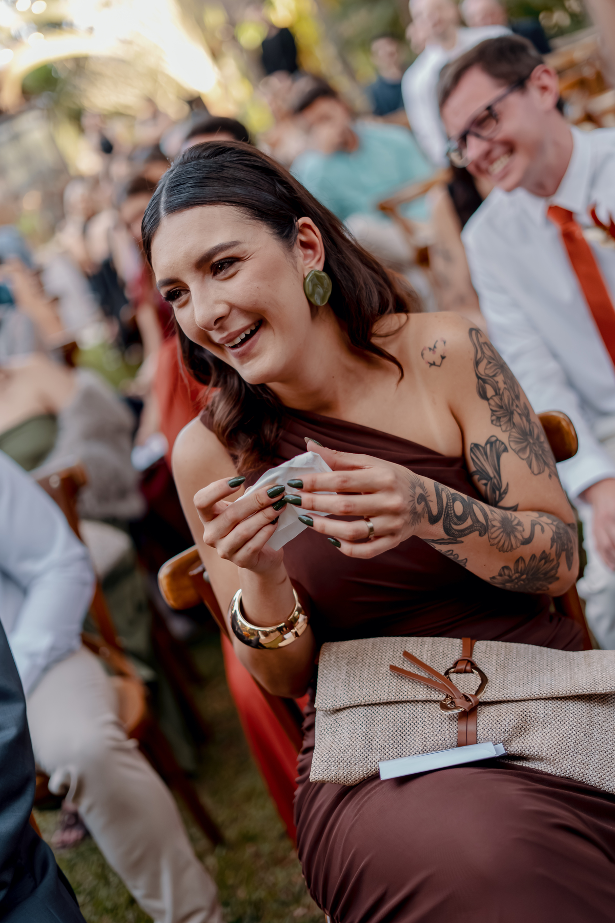 Yasmin emocionada durante a cerimônia, com um sorriso espontâneo enquanto acompanha um dos momentos marcantes do seu casamento.
