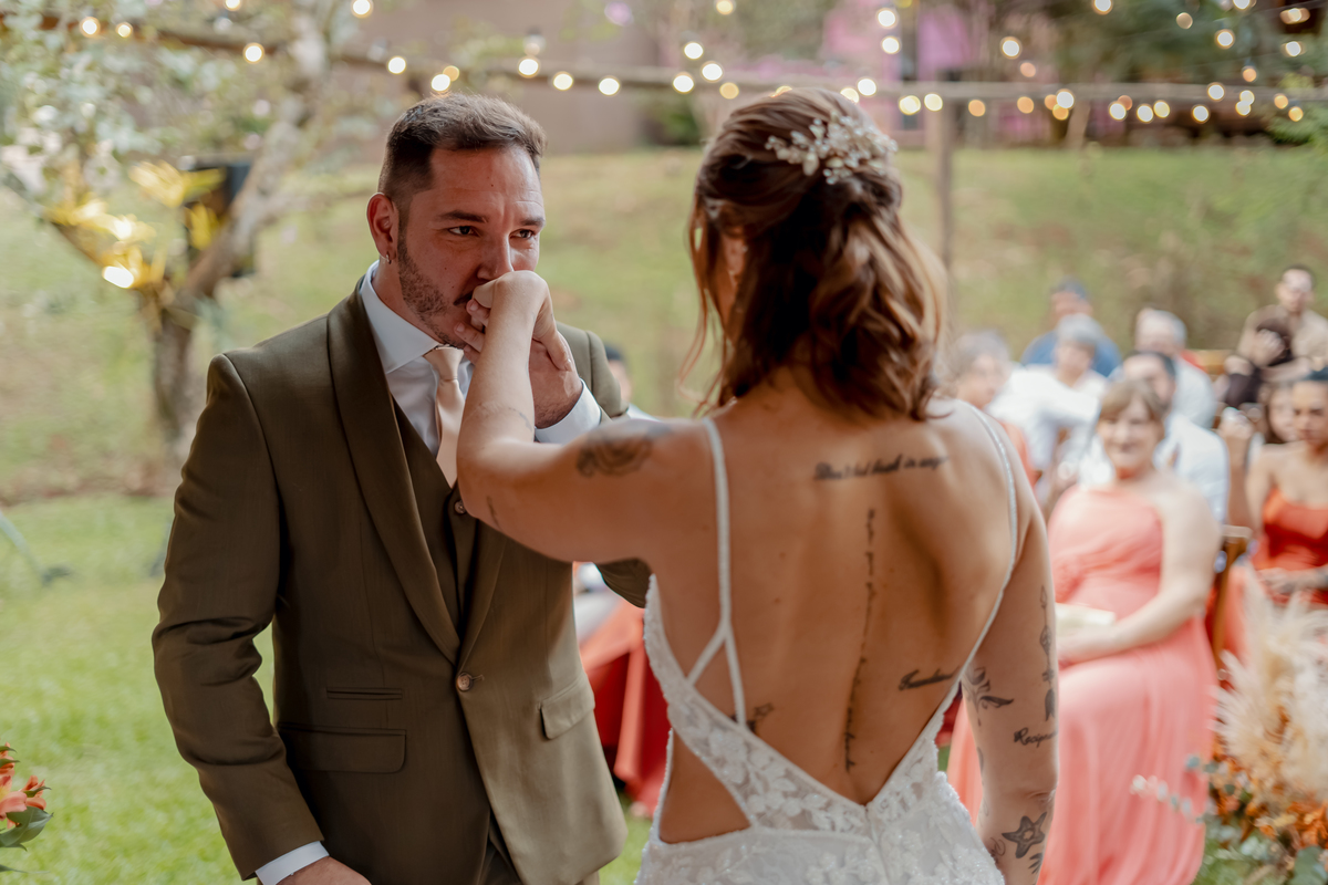 Fábio e Yasmin durante a troca de alianças, cercados pelos convidados e pela paisagem natural do casamento no campo.
