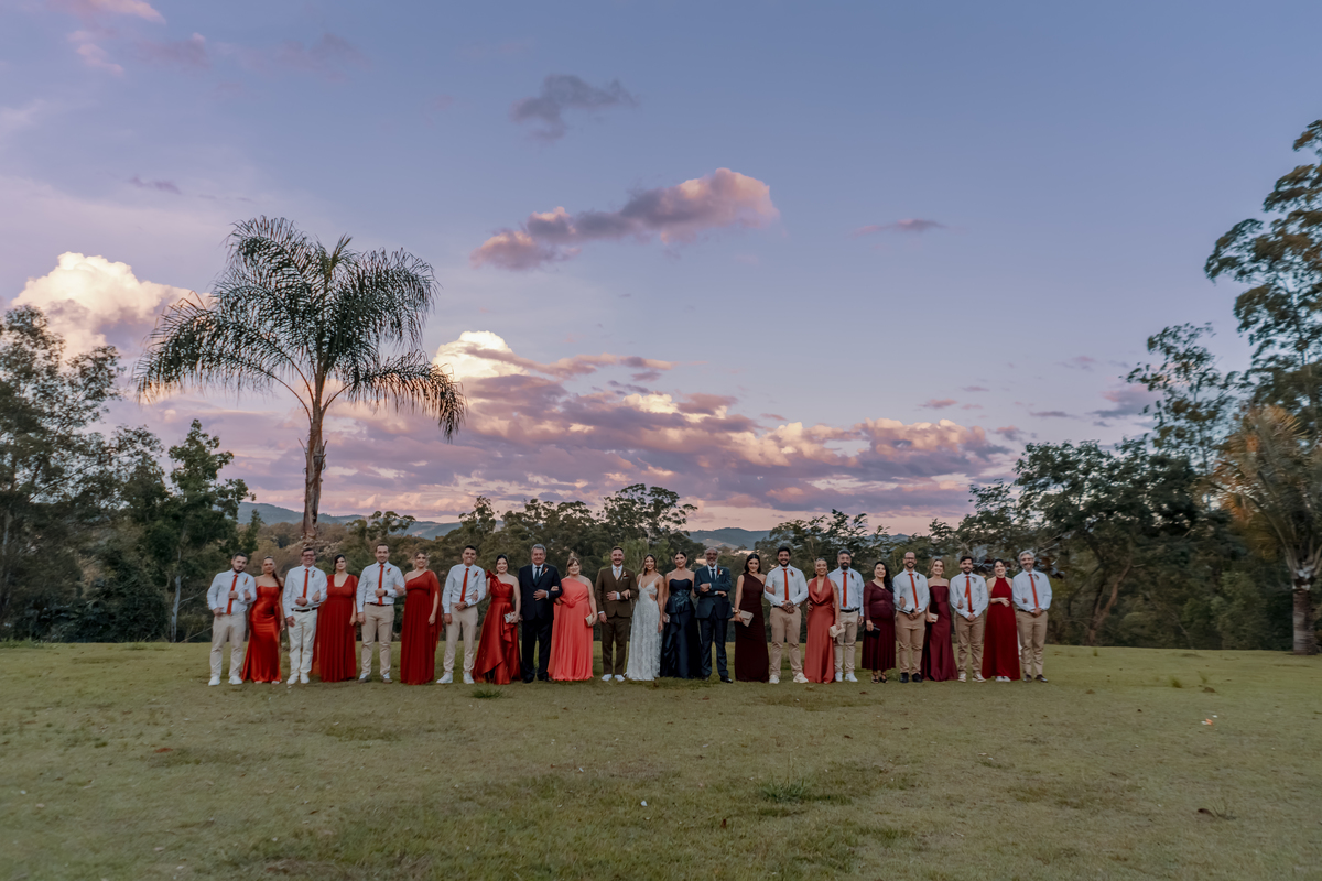 Padrinhos de Fábio e Yasmin reunidos no gramado da Fazenda Vila dos Eucaliptos, com o céu do fim da tarde compondo o cenário do casamento.