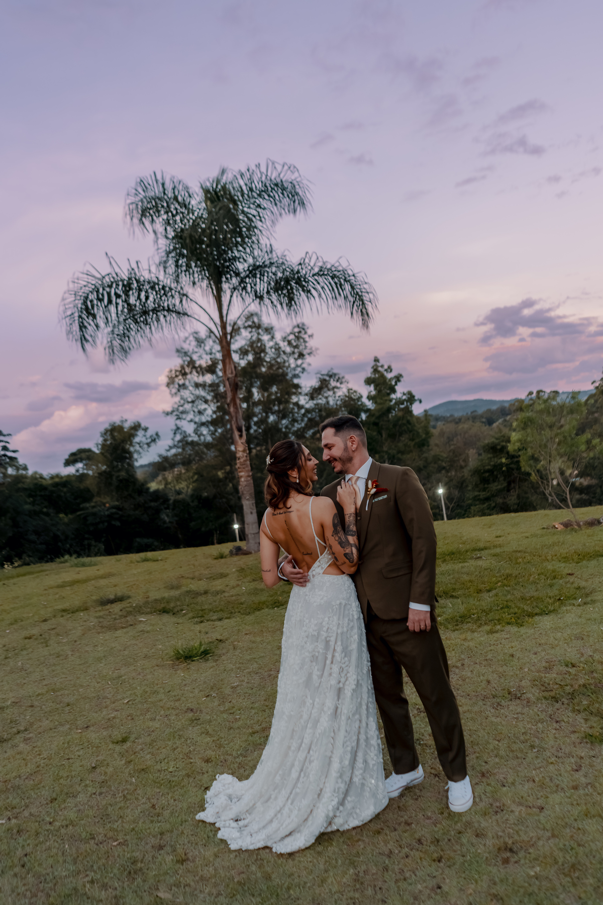 Fábio e Yasmin caminhando juntos pelo gramado da fazenda durante o ensaio de casal, com a paisagem do campo ao fundo.