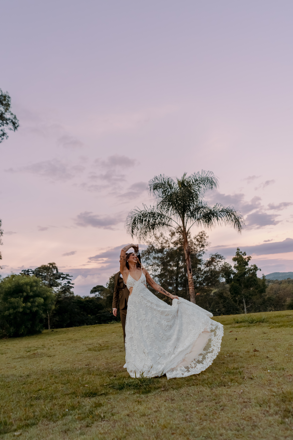 Yasmin caminhando pelo campo com o vestido de noiva, em um retrato ao ar livre marcado pela paisagem e pela luz do fim do dia.
