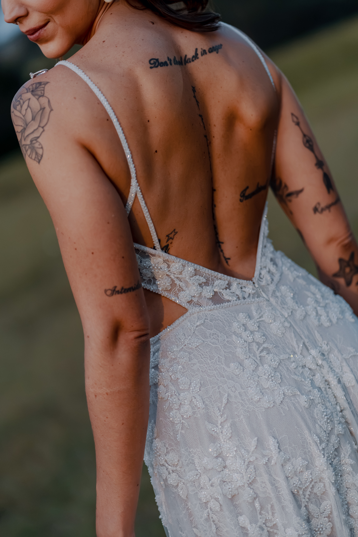 Detalhe do vestido de Yasmin durante a recepção, com a textura do tecido e as tatuagens da noiva em destaque.
