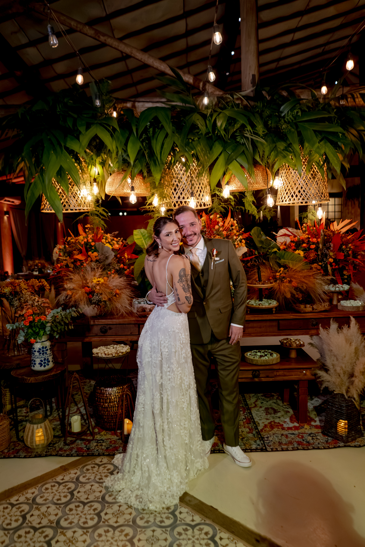 Fábio e Yasmin durante a festa de casamento, cercados pela decoração floral e pela iluminação aconchegante da recepção.