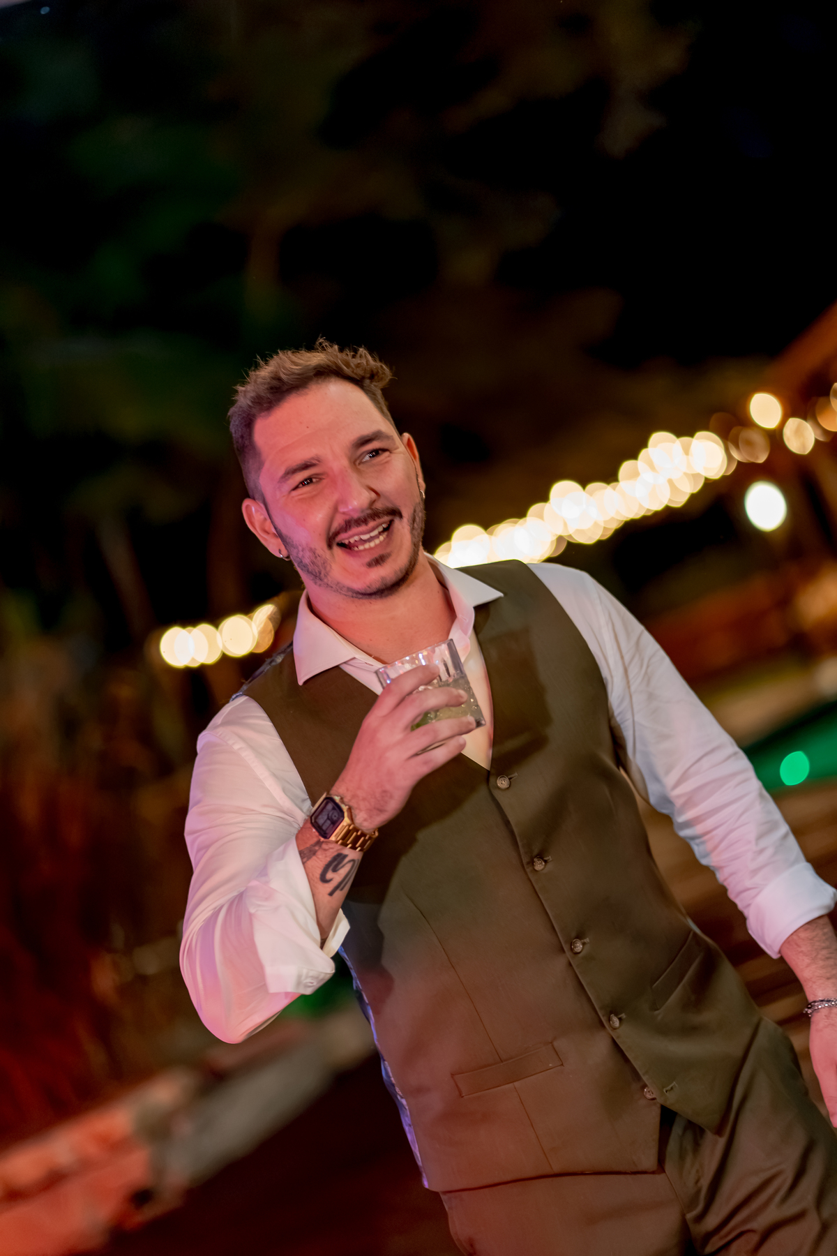 Fábio sorrindo durante a festa de casamento, em um registro espontâneo entre as luzes da recepção e os convidados.