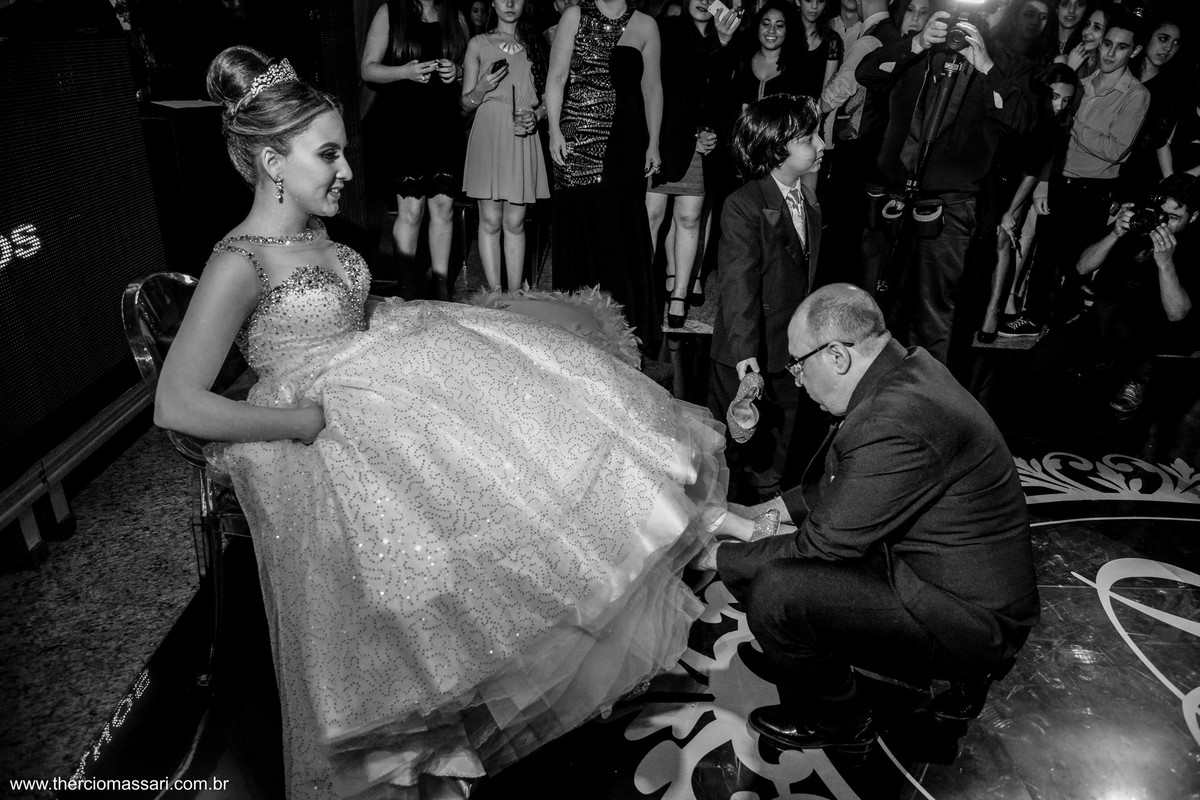o pai colocando o sapato da debutante nos pés