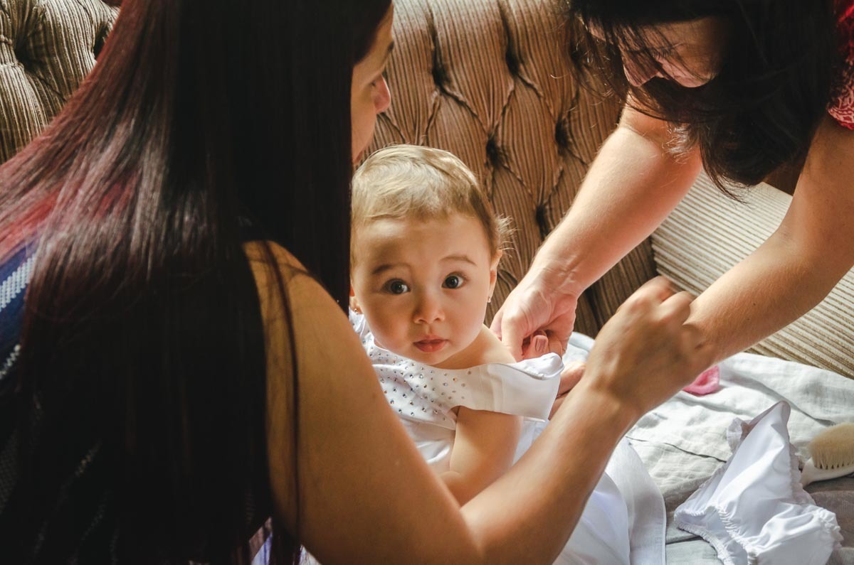 Bebê menina sendo arrumado para batismo