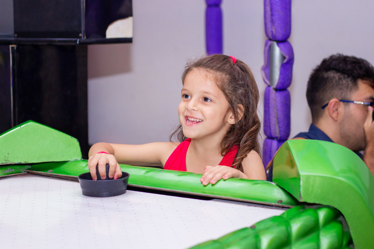 Menina brincando no air hockey
