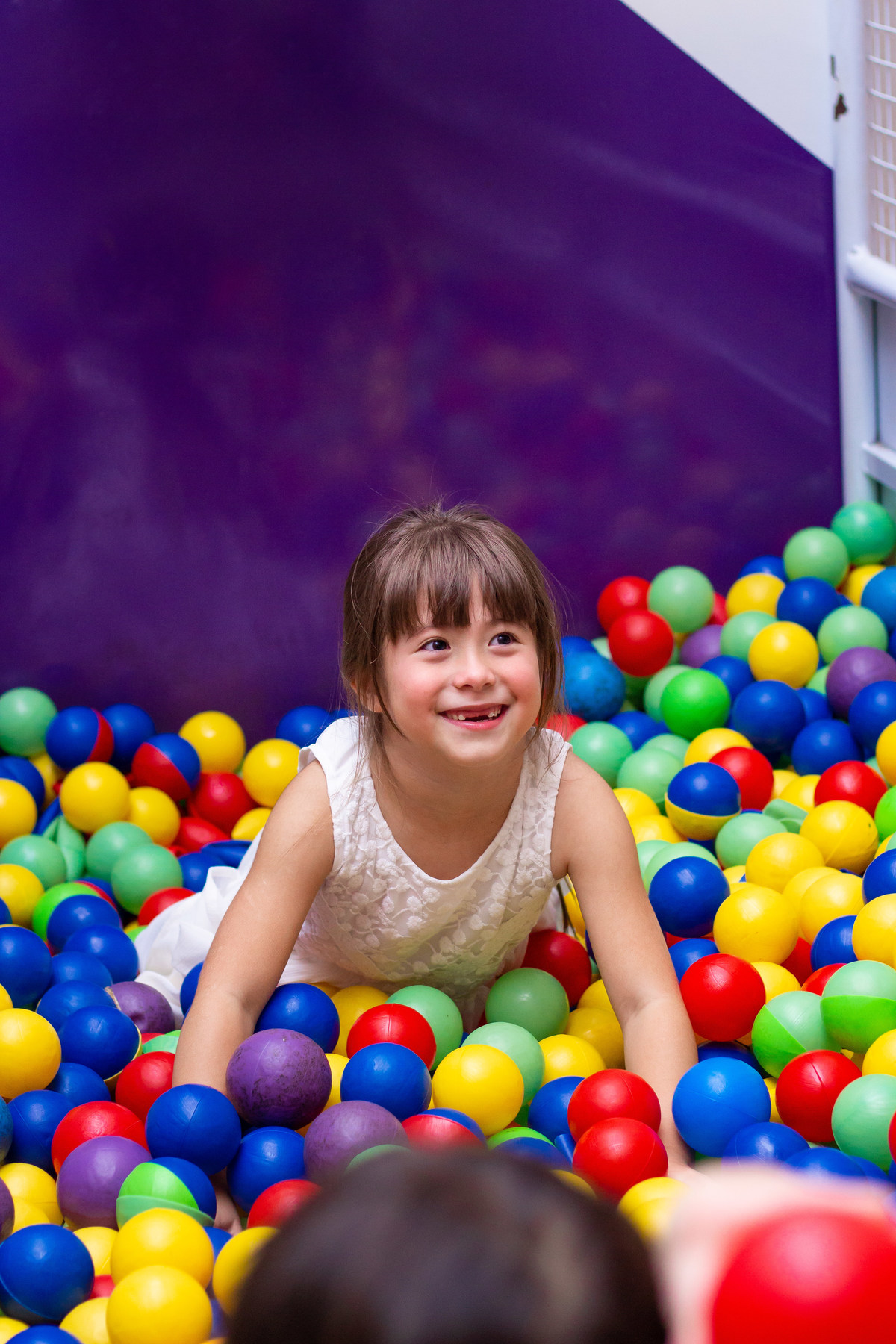 Menina sorrindo na piscina de bolinha