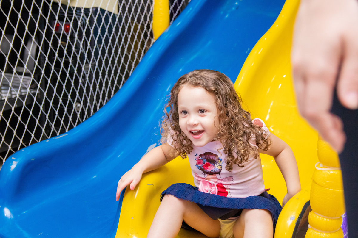 Menina sorridente descendo pelo escorregador