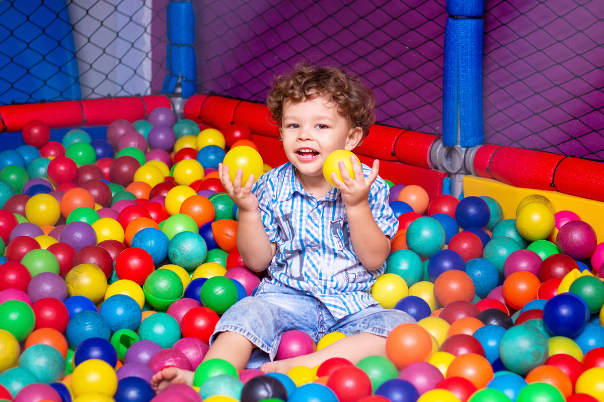 Menino sorrindo e brincando na piscina de bolinha