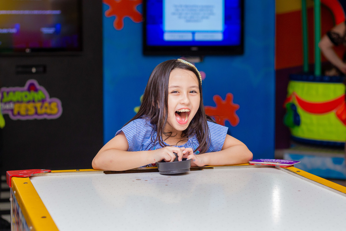 Menina brincando em air hockey