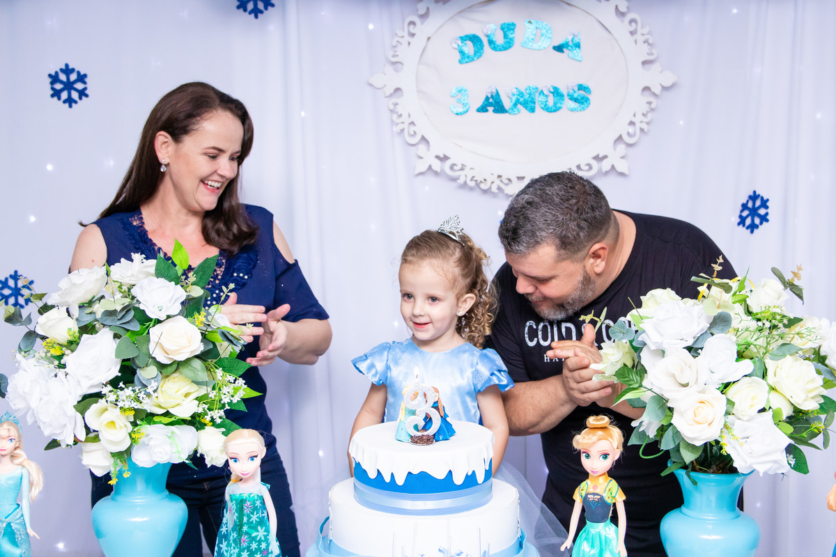 Aniversariante e seus pais na hora do parabéns