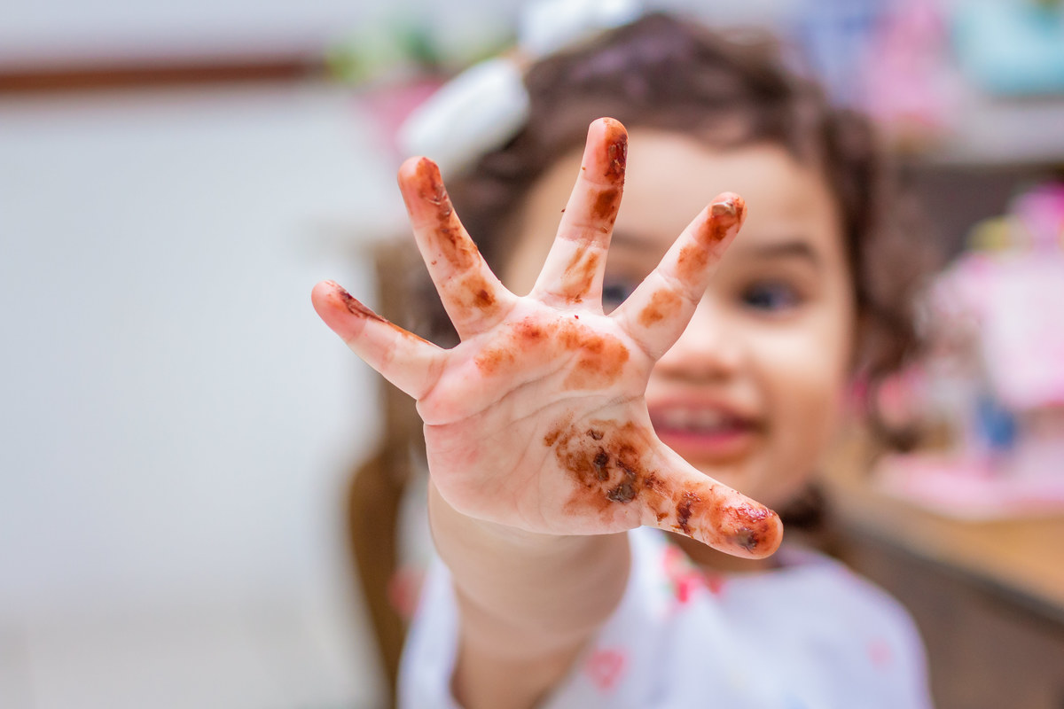 Aniversariante mostrando sua mão suja de chocolate