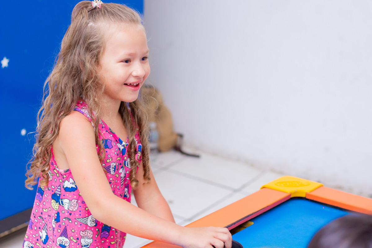 Menina sorrindo ao brincar no air hockey