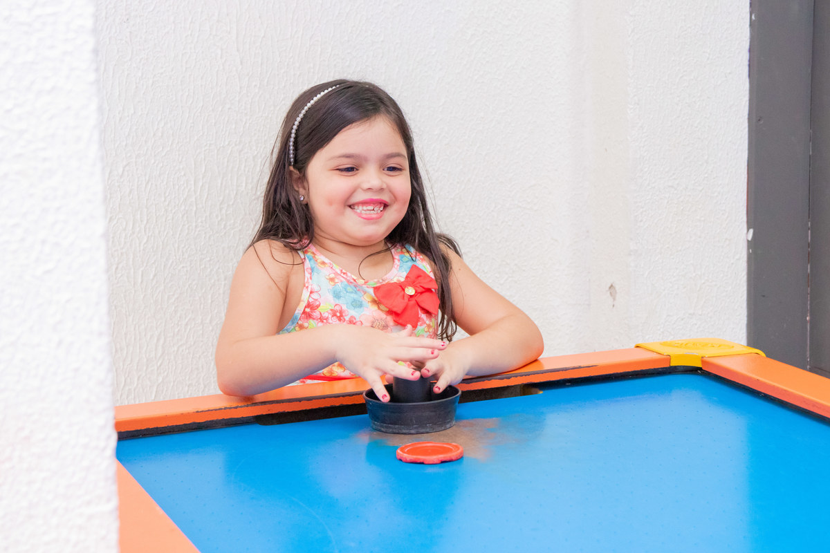Menina feliz brincando no air hockey