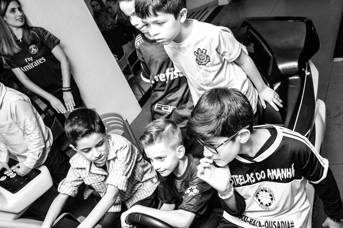 Aniversariante e seus amigos concentrados brincando de dirigir, P&B