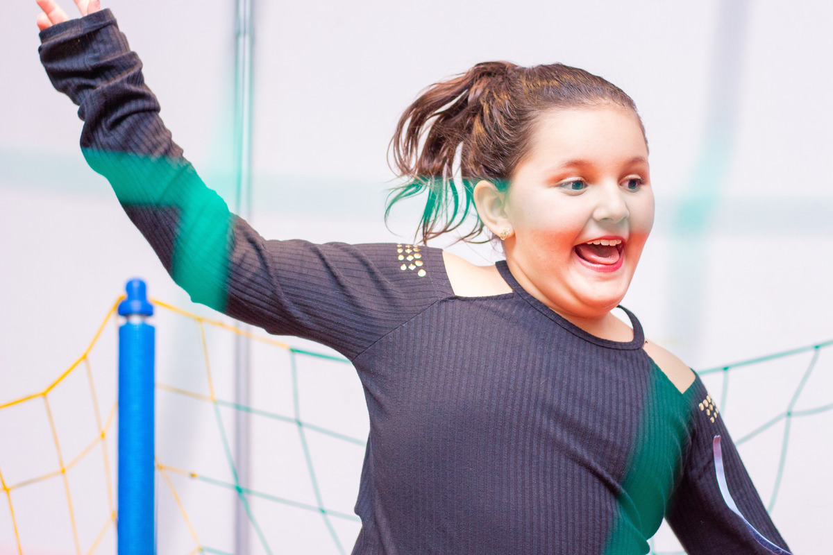 Menina feliz pulando na cama elástica